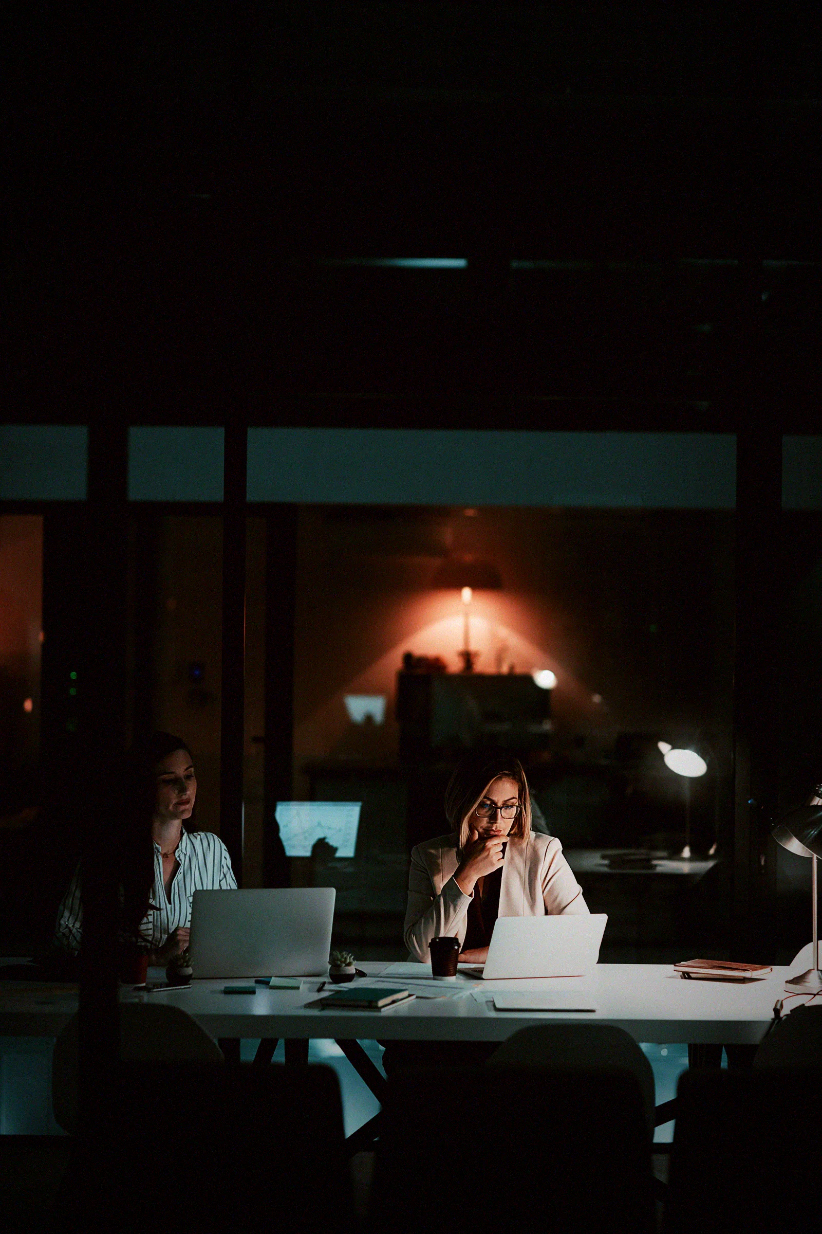 An employee working late with a laptop and printed documents, using AI tools no one on the security team approved.